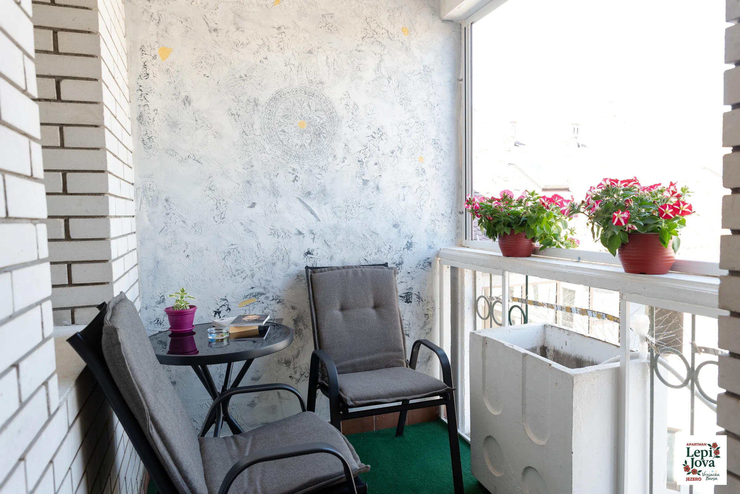 Zastakljena terasa apartmana Jezero sa foteljama i cvećem