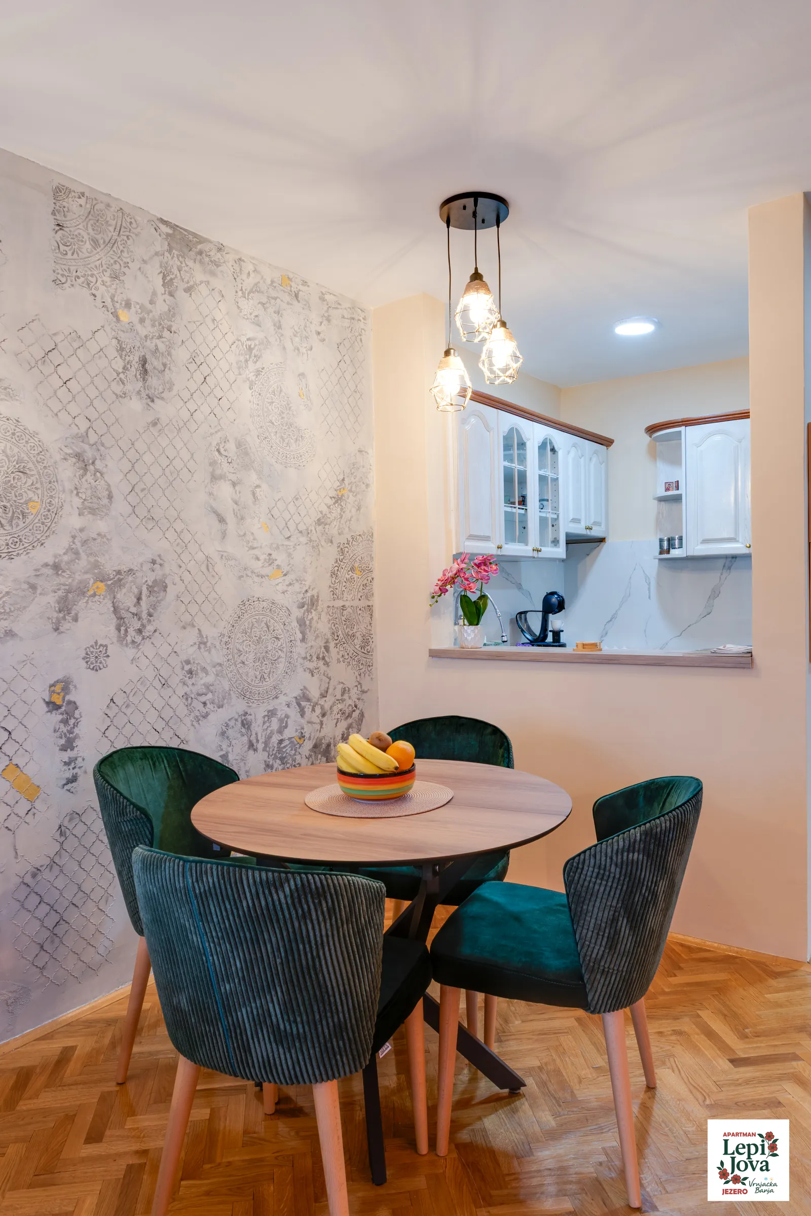 Trpezarijski sto sa zelenim tapaciranim stolicama u apartmanu Jezero