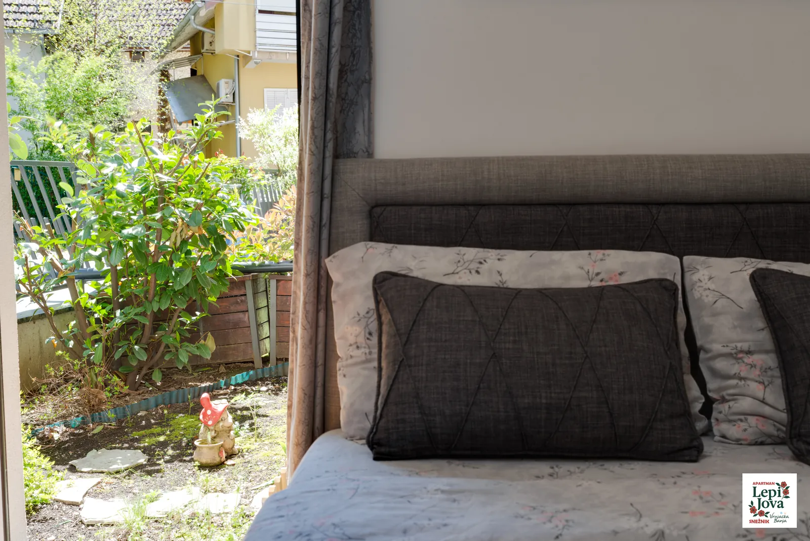 Pogled iz spavaće sobe apartmana Snežnik na zelenu baštu